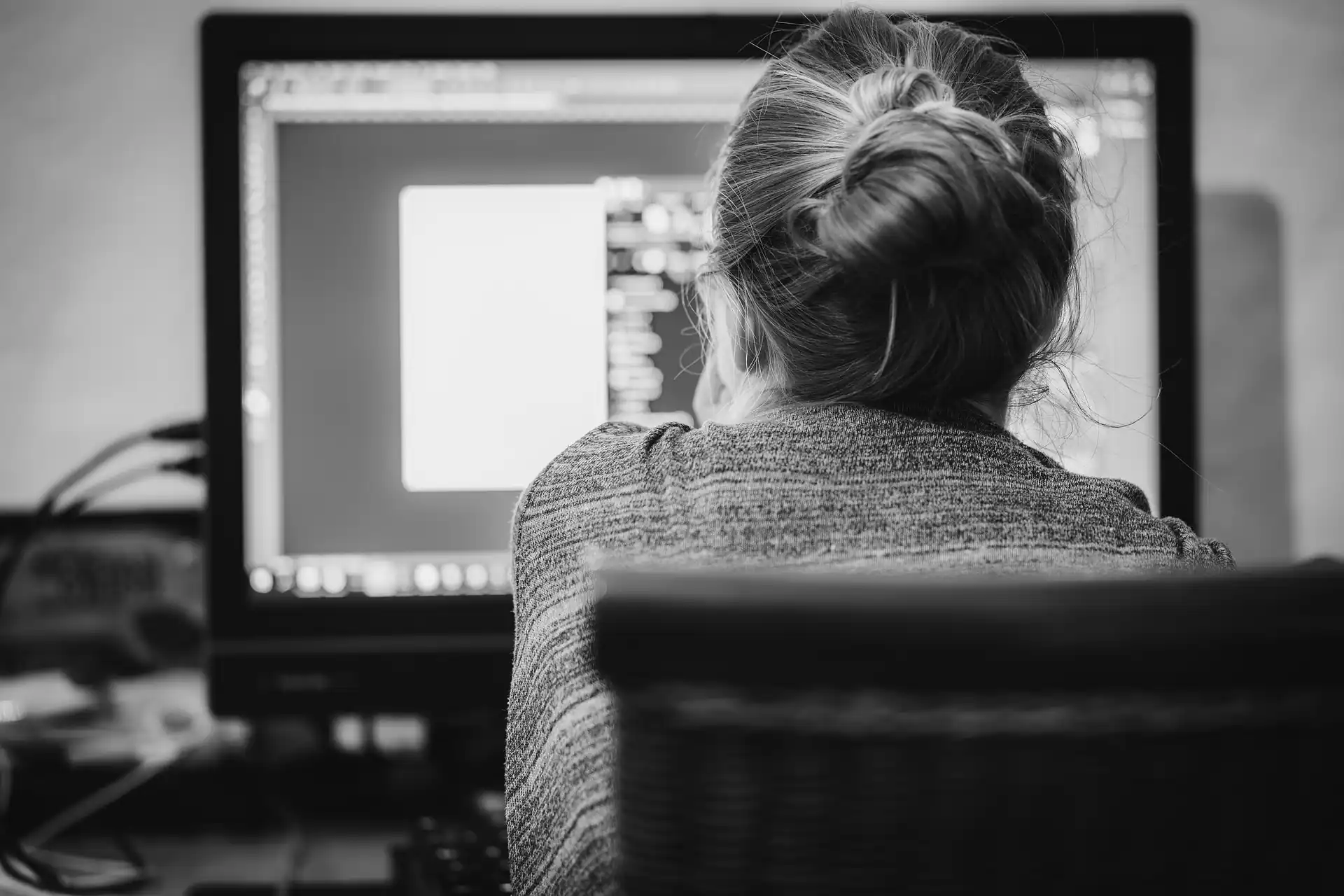 A black and white image of a woman from behind sat at a computer. freelance digital marketing strategist in Kerala
